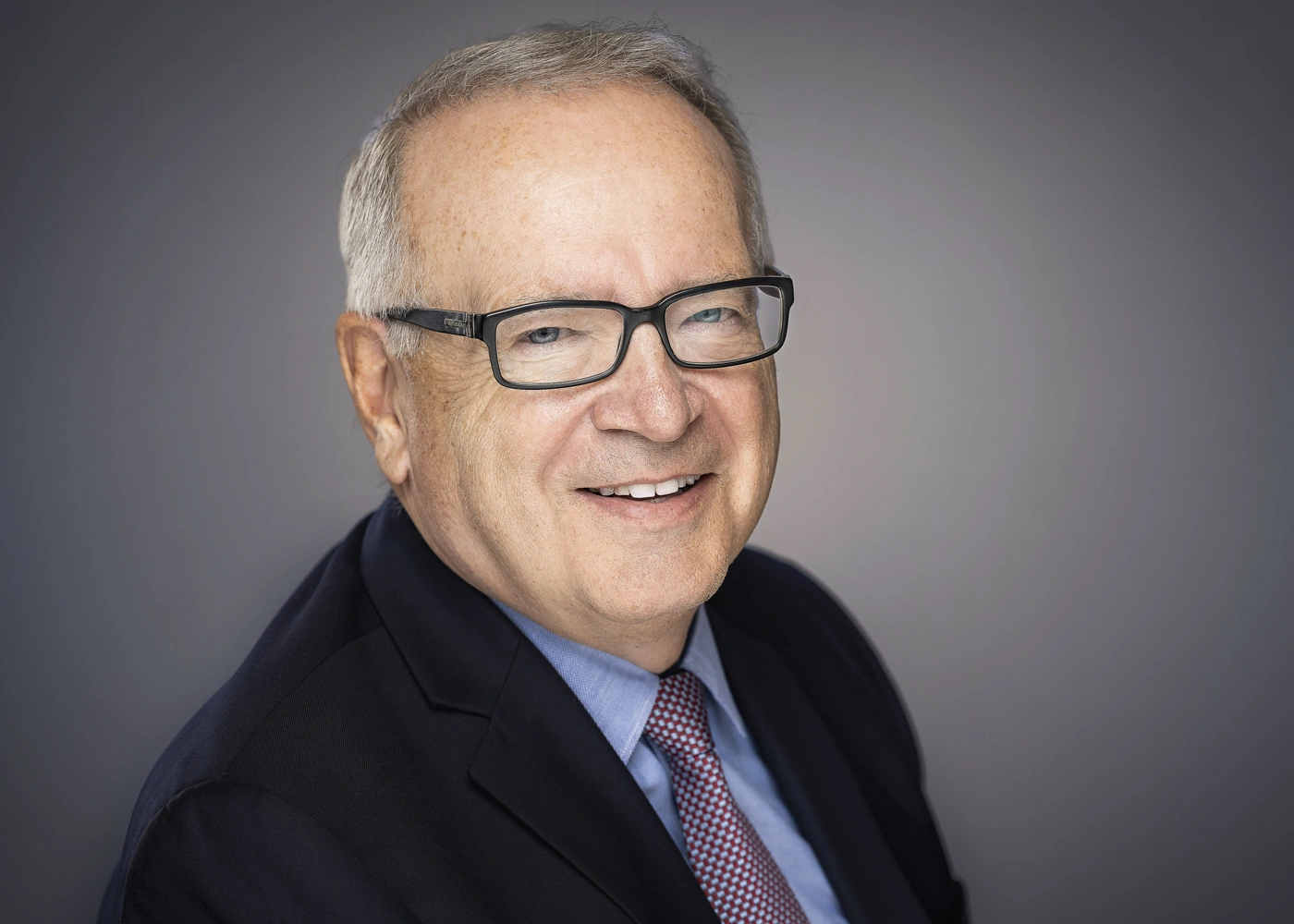 Studio Headshot of a Business Executive wearing glasses and a tie.